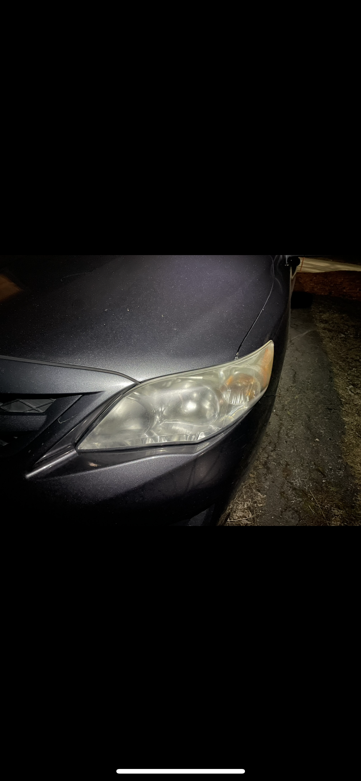 Foggy headlight before restoration on dark Toyota Corolla at night
